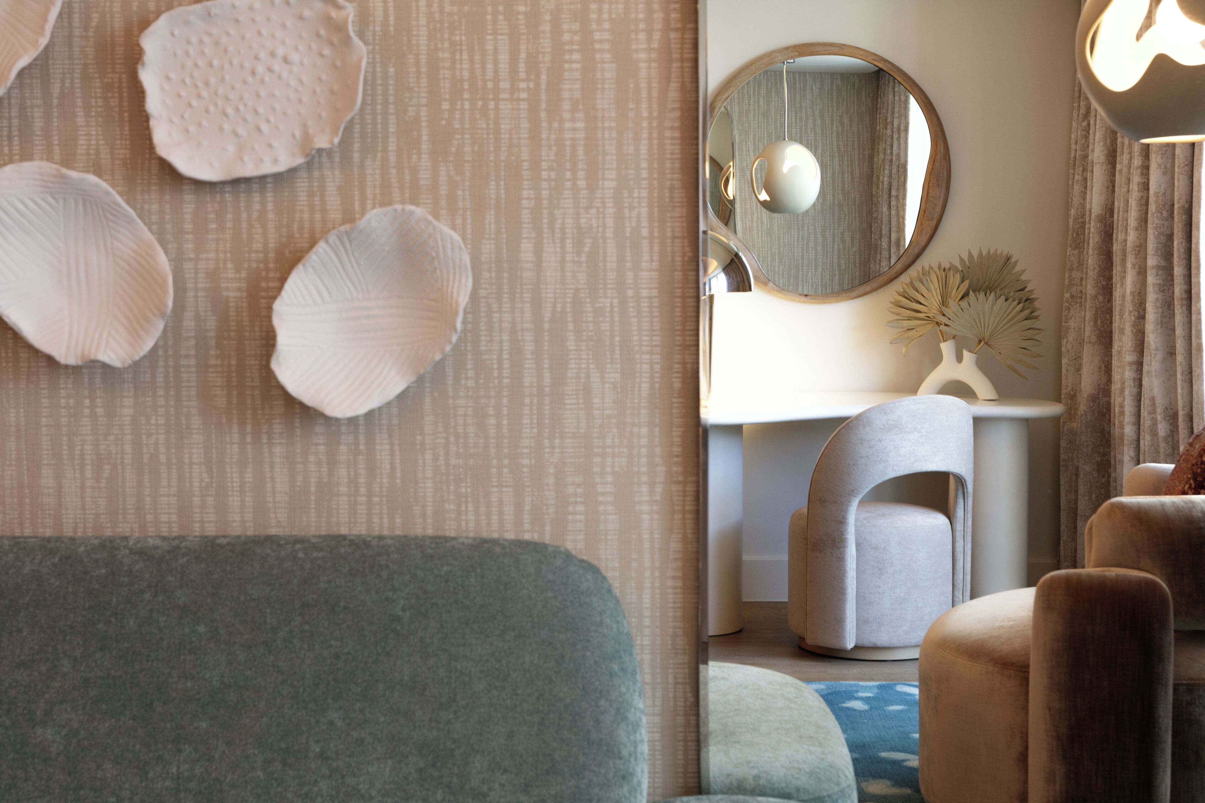 A modern interior with a sofa, a round mirror, and a decorative wall piece.