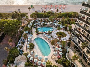 Un resort con piscina, tumbonas, sombrillas y zona de playa.