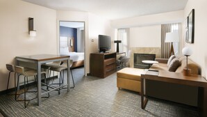 Quarto de hotel com escrivaninha, dois banquetes, sofá, televisão e uma pequena mesa.