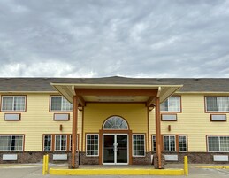 A two-story building with a yellow facade, a covered entrance, and a brick lower level.