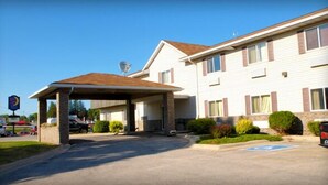 A two-story motel with a covered parking area and a satellite dish on the roof.