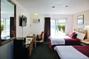 Habitación de hotel con dos camas, un escritorio, una silla, un televisor y una ventana con cortinas.