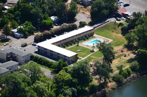 Vista aérea de un edificio con piscina, rodeado de vegetación y un río.