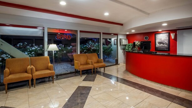 Un vestíbulo con dos sofás, un mostrador de recepción y una escalera.