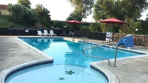 Una piscina con jacuzzi, sillas de descanso y sombrillas.