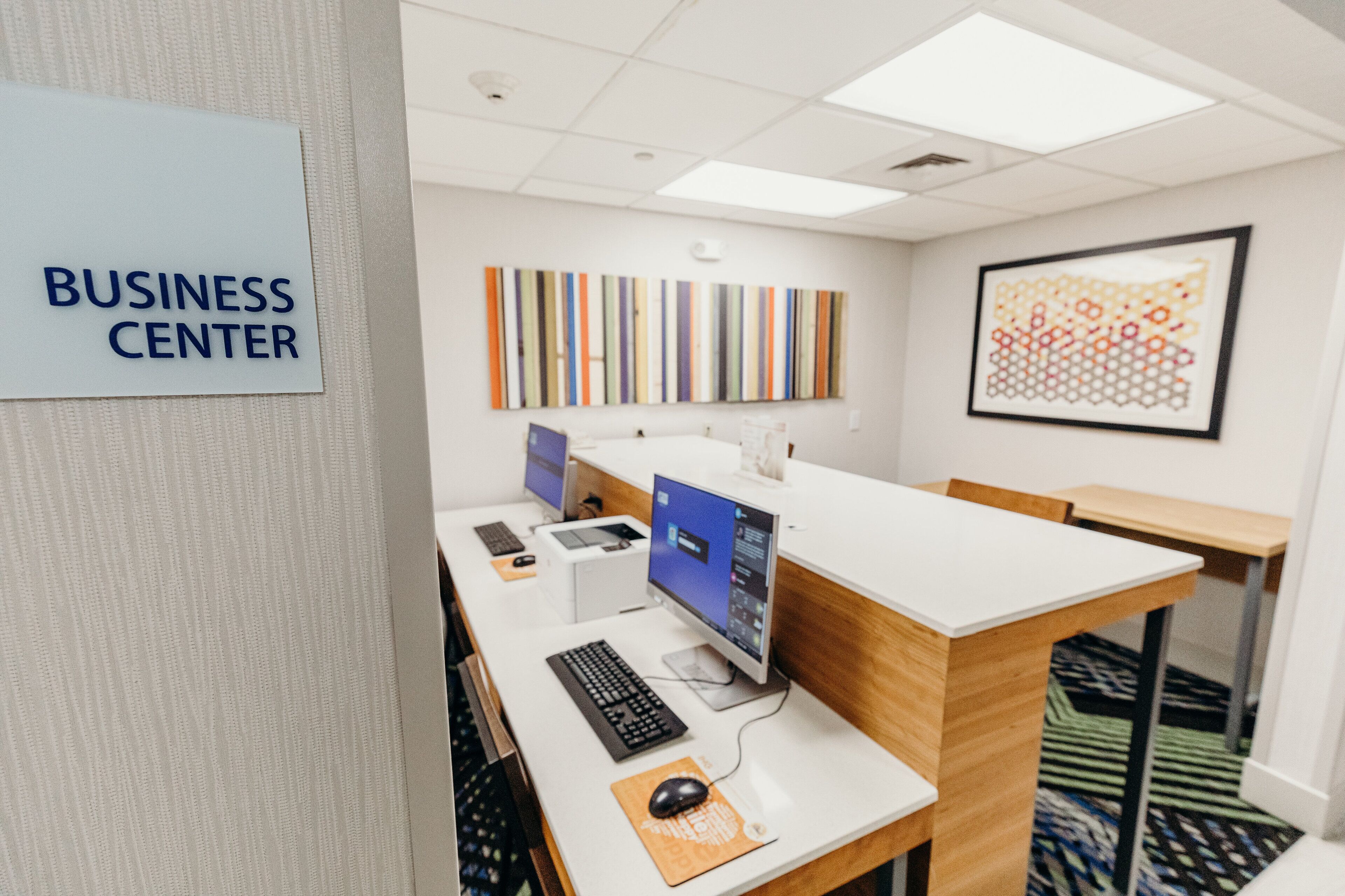 A business center with a computer desk, a keyboard, a mouse, and a monitor.