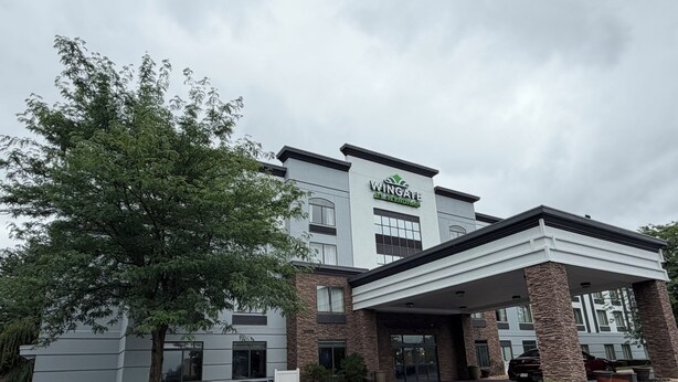 A Wingate hotel with a covered entrance, stone pillars, and a parking lot.
