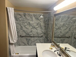A bathroom with a marble shower wall, a bathtub, a sink with a mirror, and a towel rack. - Wingate by Wyndham Harrisburg Near Hershey (Harrisburg)