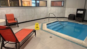 A swimming pool with a safety sign, a chair, and a small table.