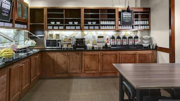 Un coin cuisine avec des meubles en bois, un comptoir où sont disposés des aliments et un espace dédié au café.