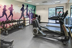 Un gimnasio con cintas de correr, mancuernas y pesas.