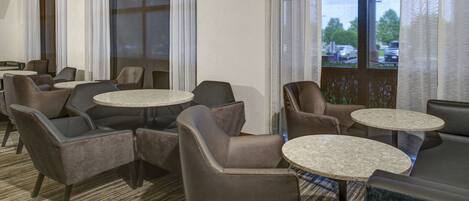 A hotel lobby with multiple seating areas, including sofas and round tables.