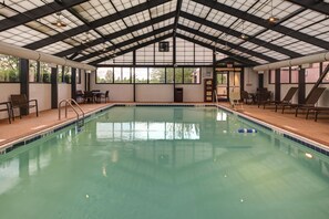 An indoor swimming pool with clear water, surrounded by lounge chairs and tables, under a high ceiling with skylights. - Hyatt Place Boise/Towne Square (Boise)
