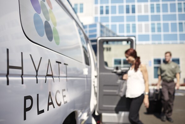 A white van with "HYATT PLACE" written on it, parked in front of a building with a blue and white facade. - Hyatt Place Boise/Towne Square (Boise)