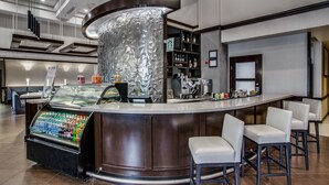 Un espace bar moderne doté d’un comptoir incurvé, de sièges, d’un distributeur de boissons et du logo de Starbucks.