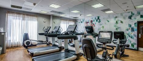 A gym with treadmills, elliptical machines, and stationary bikes.