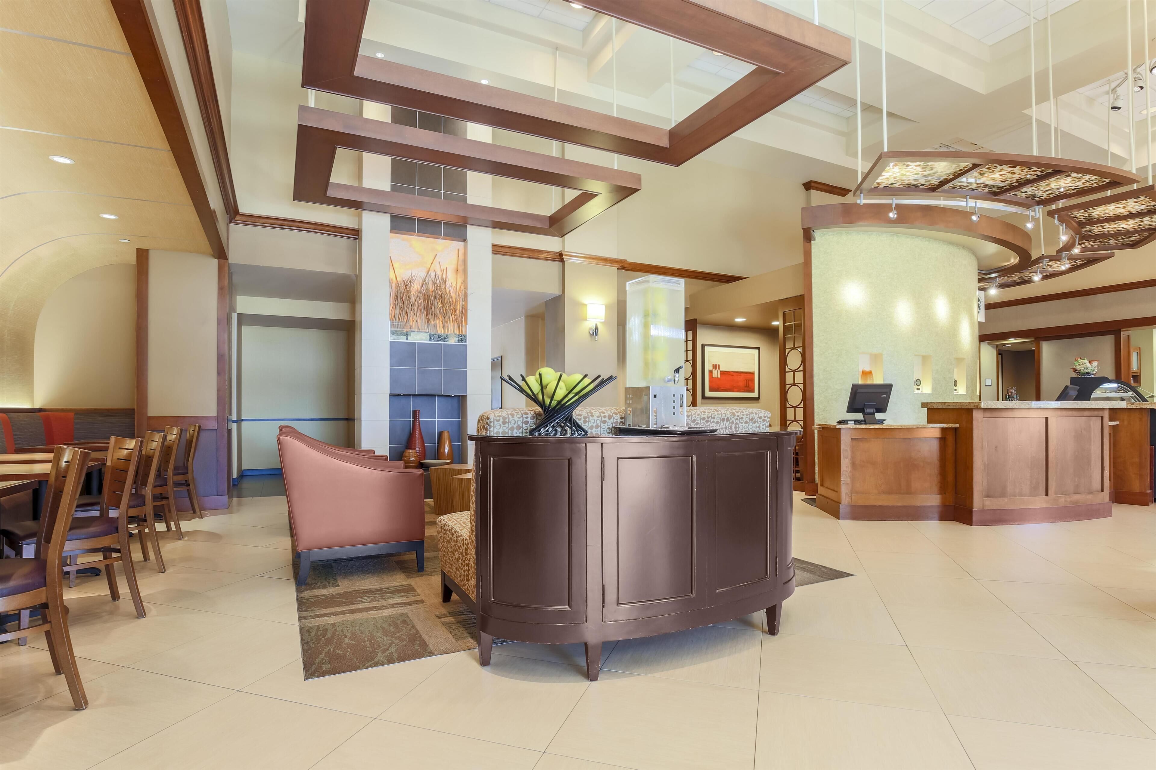 A hotel lobby with a reception desk, seating area, and a large window.