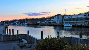 A waterfront view with a wooden dock, a bench, and a row of buildings along the water.