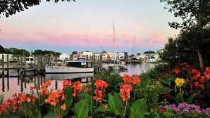 A marina with boats docked, surrounded by lush greenery and flowering plants. - Hyatt Place Mystic (Mystic)