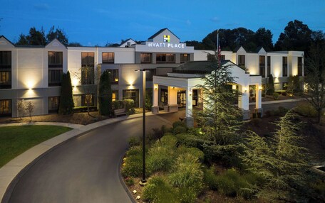 A modern hotel with a well-lit entrance, a covered outdoor area, and landscaped surroundings.
