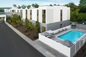 A modern hotel with a swimming pool, outdoor seating, and a well-maintained garden. - Hyatt Place Mystic (Mystic)
