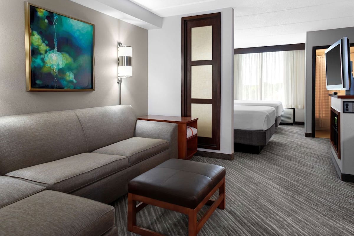Une chambre d’hôtel avec un canapé, une petite table, un lit, une télévision et un tableau au mur.