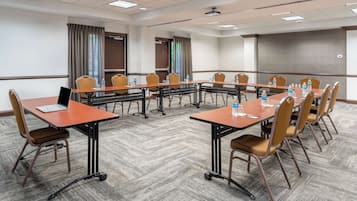 A conference room with a long table, chairs, laptops, water bottles, and a projector screen.
