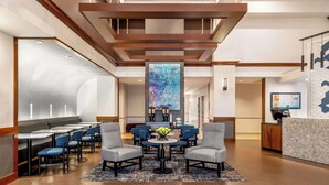 A hotel lobby with a reception desk, seating area, and a large abstract artwork on the wall. - Hyatt Place Mystic (Mystic)