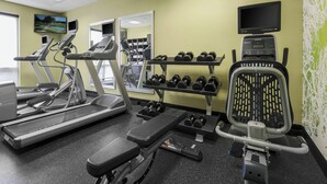 Et fitnessrum med løbebånd, håndvægte og en motionscykel.