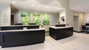 Et receptionsområde med to sorte receptionistskeletter, en indtjekningsdisk og en skilt til kontoret.