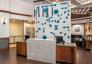 Un mostrador de recepción de diseño moderno, con una pared de motivos geométricos y una encimera tipo mármol.
