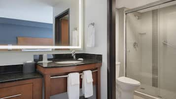 A modern bathroom with a large mirror, a sink, a toilet, and a glass-enclosed shower.