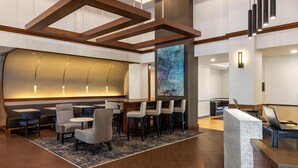 A modern hotel lobby with a reception desk, seating area, and a large abstract painting on the wall.