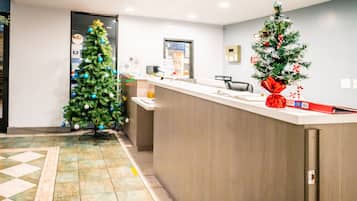 Zona de recepción con un árbol de Navidad, un mostrador de recepción y piso de baldosas.