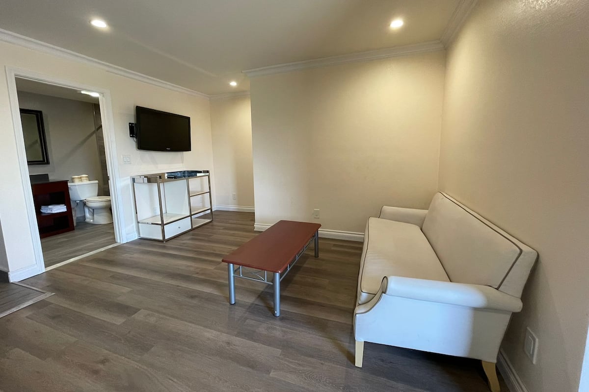 A modern living room with a white sofa, a wooden coffee table, and a TV mounted on the wall.