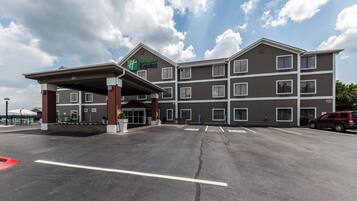 Edifício Holiday Inn Express com entrada coberta, diversas janelas e estacionamento com vagas para deficientes.