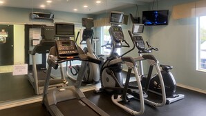 Une salle de sport équipée de tapis de course, d’appareils elliptiques et de vélos d’appartement.