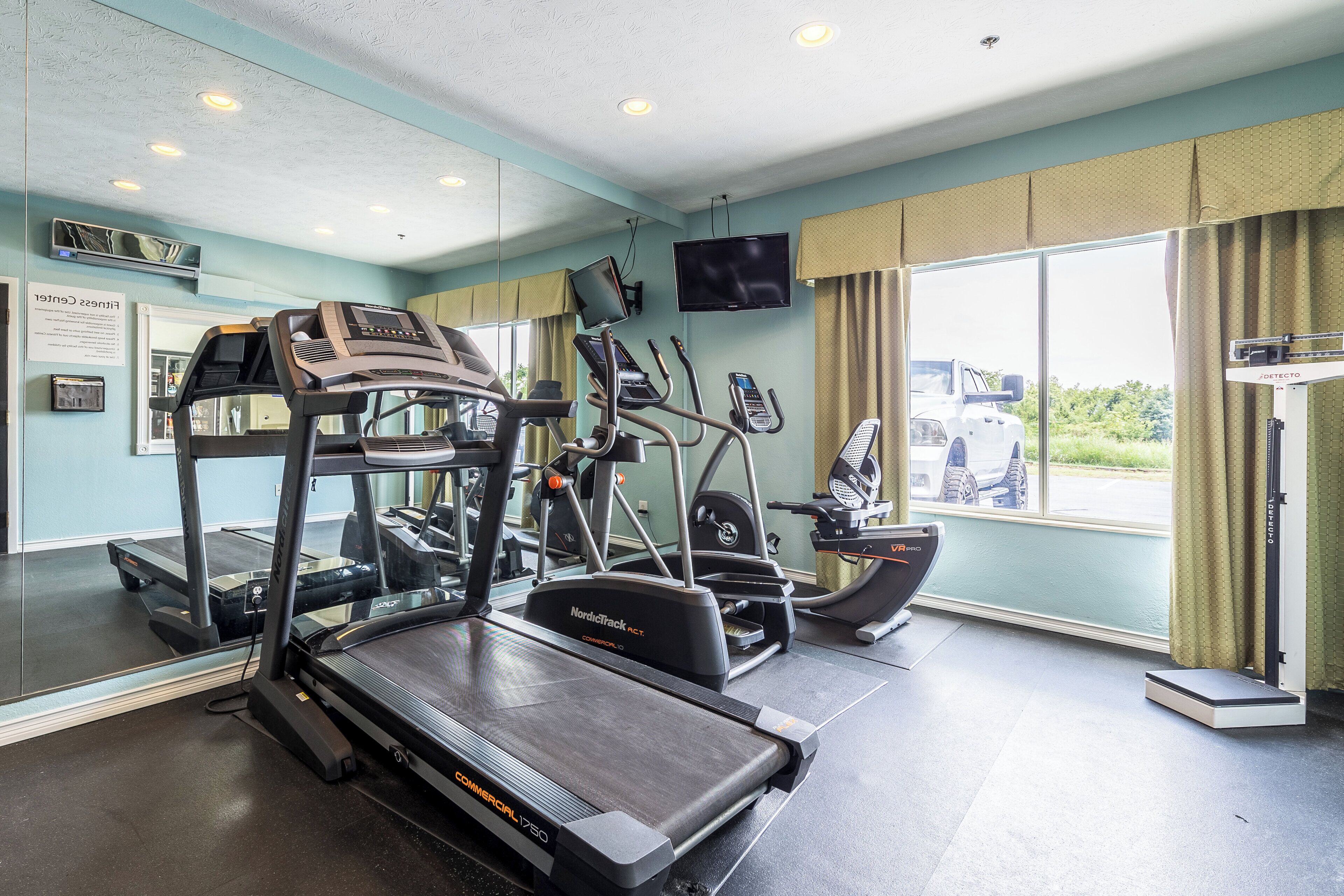 Un gimnasio con cintas de correr, elípticas y una bicicleta estática.