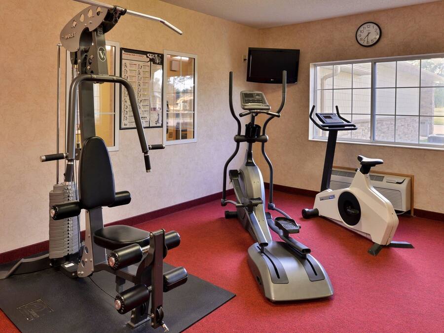 Un gimnasio con equipamiento de ejercicio, un reloj y un ventanal.