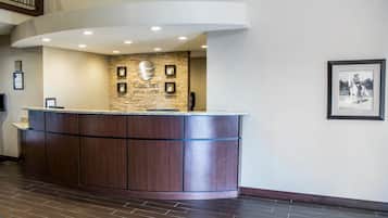 A reception desk with a stone wall backdrop, a framed picture on the wall, and a wooden floor.