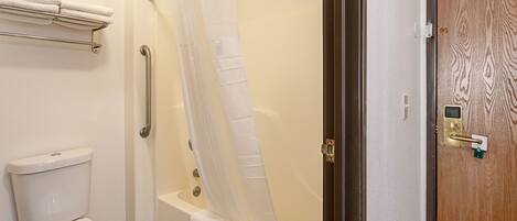 Un baño con inodoro, bañera con cortina de ducha, toallero y puerta de madera con cerradura.