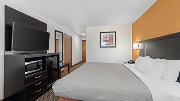 Una habitación de hotel con una cama, televisión, minibar y puerta.