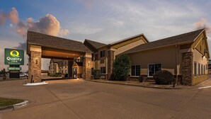 A hotel with a covered entrance, stone facade, and a sign indicating an indoor pool. - Quality Inn Dodge City (Dodge City)