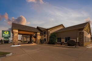 Un hotel con entrada cubierta, fachada de piedra y un letrero que indica una piscina interior.