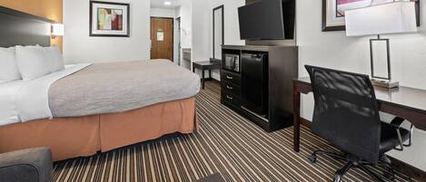 Een hotelkamer met een bed, bureau, stoel, televisie en kunstwerken aan de muren.