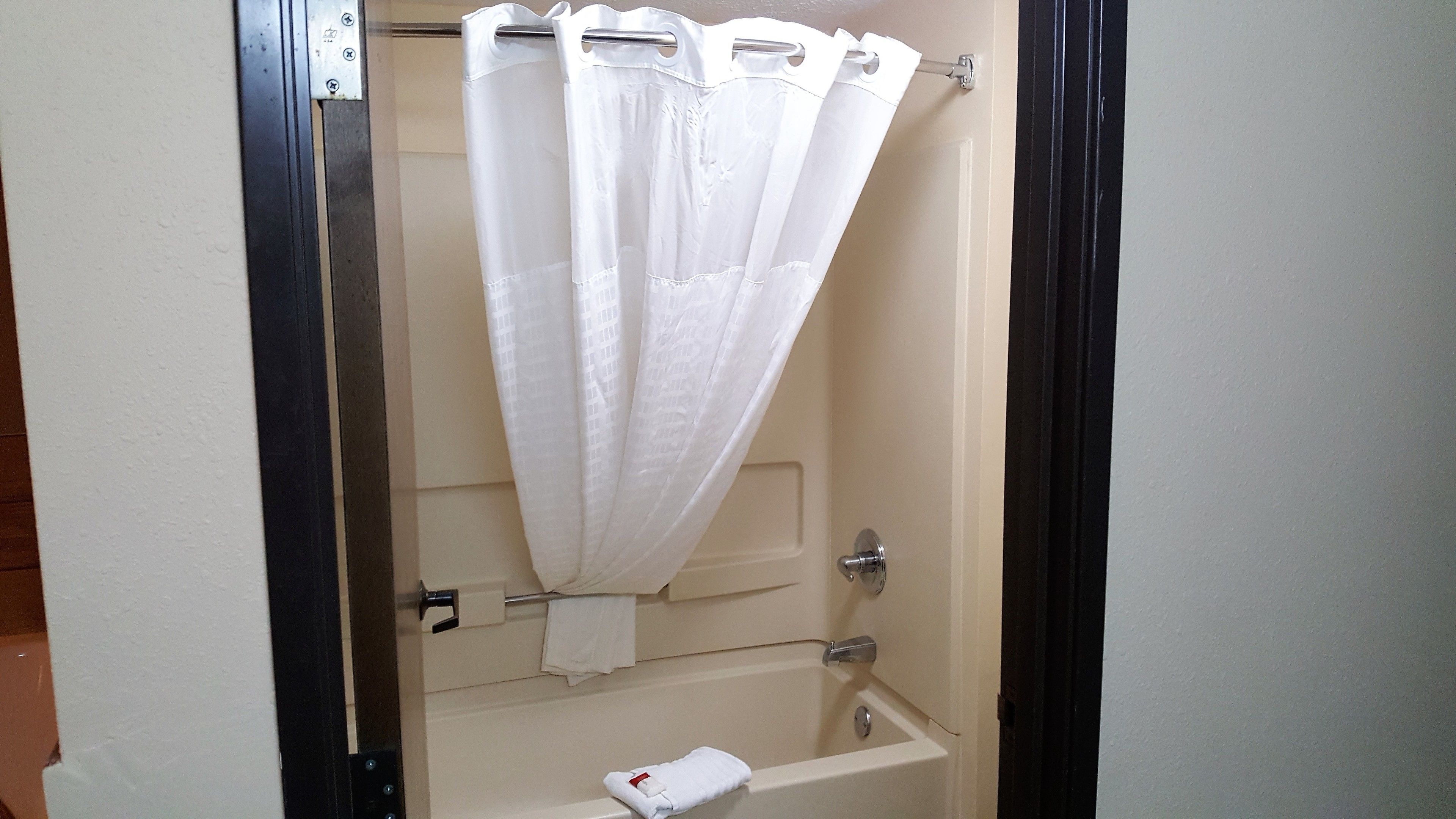 A bathroom with a bathtub, a shower curtain, and a towel rack.