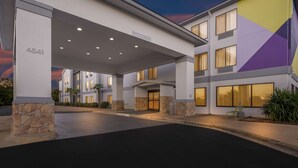A hotel entrance with a covered walkway, stone pillars, and a clear sky. - Spark by Hilton Tuscaloosa University (Tuscaloosa)