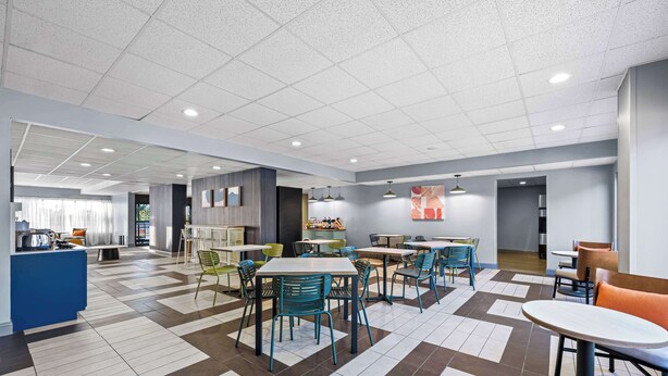 A spacious indoor area with multiple tables and chairs, a counter, and a variety of seating arrangements. - Spark by Hilton Tuscaloosa University (Tuscaloosa)