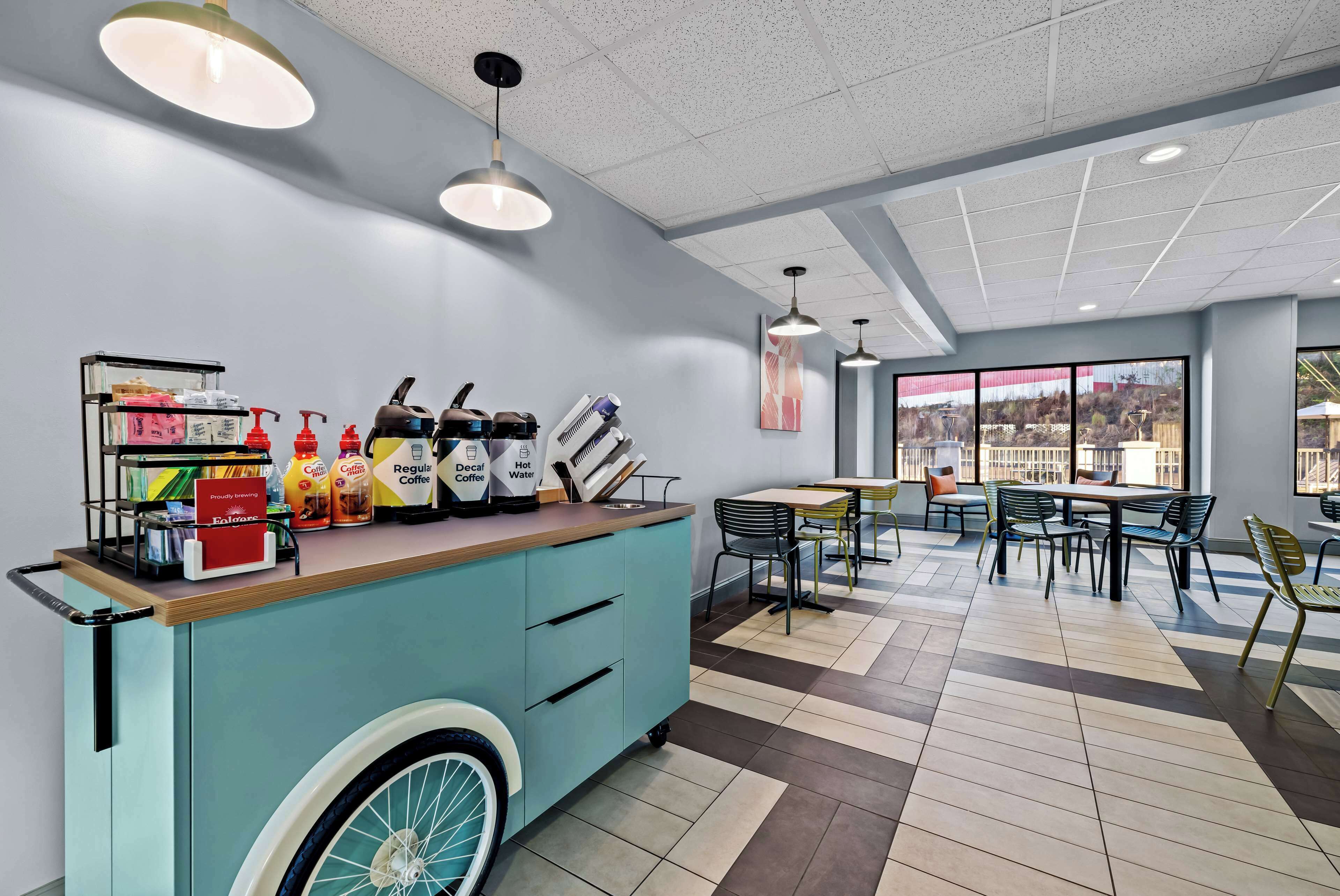 A modern cafe with a blue counter, various beverages, and a wheelchair-accessible design.