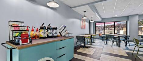A modern cafe with a blue counter, various beverages, and a wheelchair-accessible design.